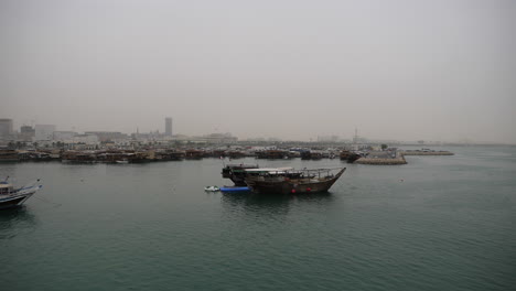 skyline of beautiful doha - traditional dhow boat mooring in foreground - doha, qatar