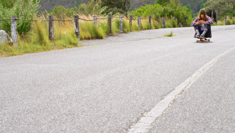 Front-view-of-young-caucasian-woman-using-mobile-phone-while-moving-on-skateboard-at-countryside-4k