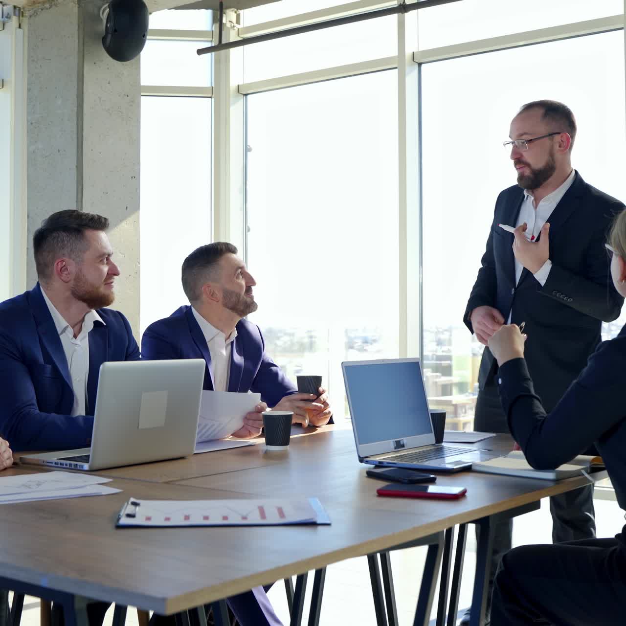 Business, technology and office concept - happy business team with laptop computers, documents and coffee. Meeting before the start of the working day to discuss a business plan