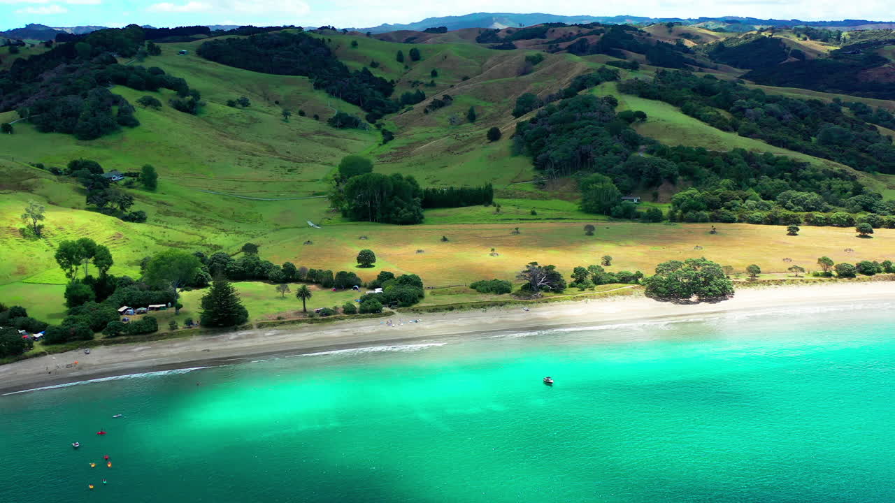 camping en la playa de te muri durante el verano con montañas verdes en nueva zelanda