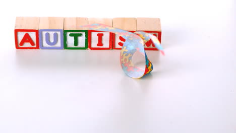 cinta de concienciación cayendo delante de los bloques de cartas de autismo