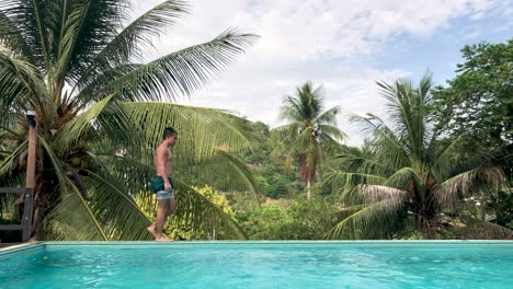 tourist walking at the edge of an infinity pool in koh tao, thailand on a sunny day - static shot