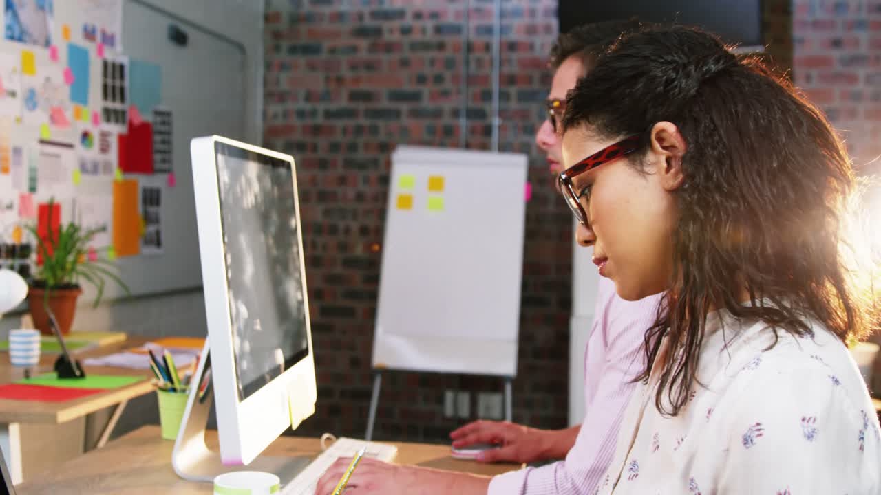 Businesswoman sitting with coworker while working on computer