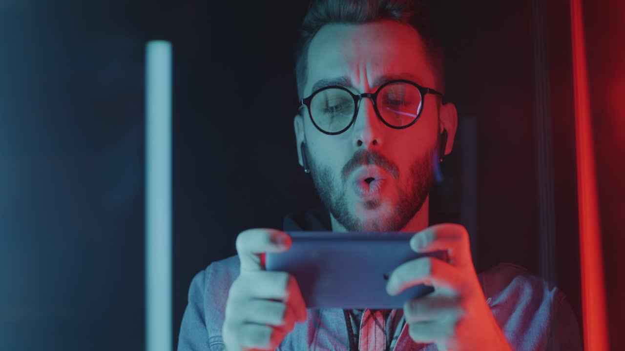 Excited Gamer Celebrating Mobile Game Victory in Neon Lighting