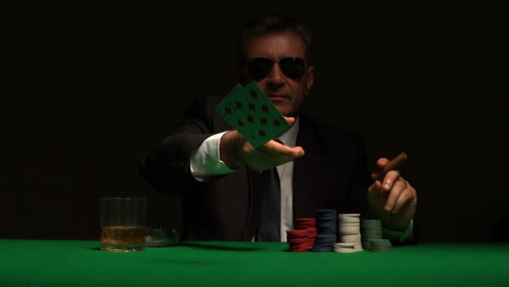 cool gambler playing poker in sunglasses