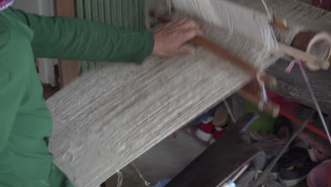 unrecognizable woman weaving natural fibers on a traditional weaving loom