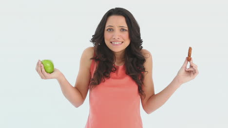 A-indecisive-woman-tries-to-choose-between-an-apple-and-a-cookie