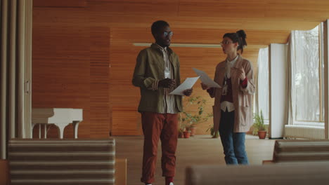 man and woman speaking about documents in library auditorium