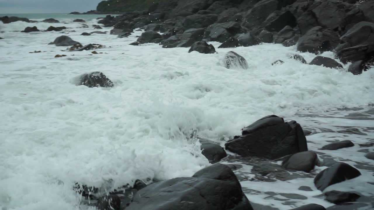 흐린 날에 절벽, 뉴질랜드 해변에서 바위를 치는 파도