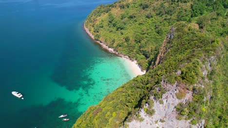 aerial-view-of-a-tall-limestone-mountain-cliff-at-Ko-Kai-with-a-view-of-the-turquoise-ocean-below-surrounded-with-pristine-white-sand-beach-in-Krabi-Thailand