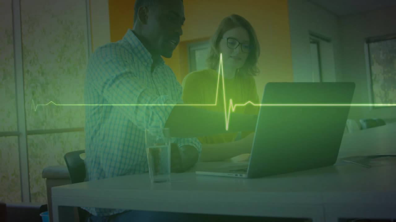 Two colleagues pointing laptop screen while neon ECG line sweeping left guiding health discussion