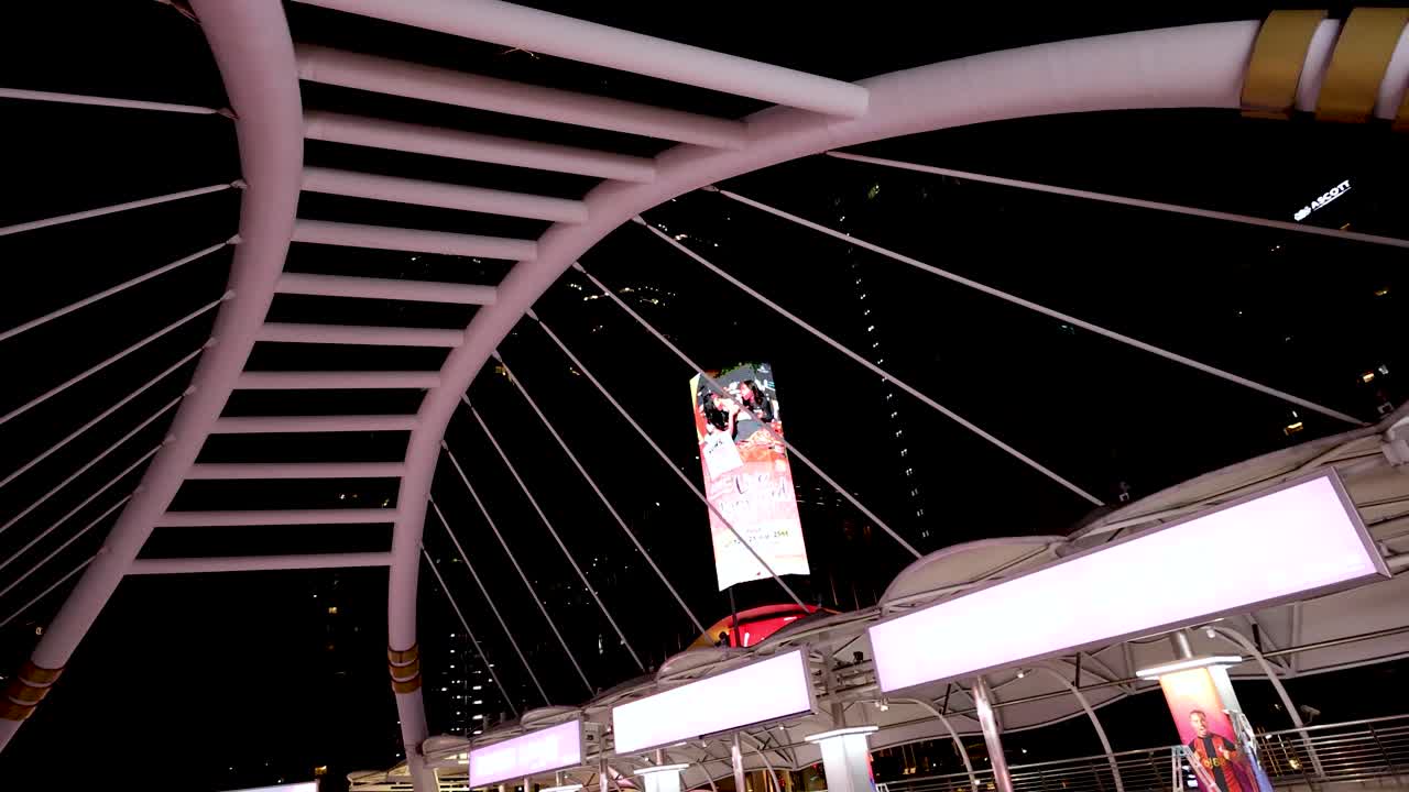 Camera pans upward across illuminated Chong Nonsi Bridge, highlighting modern architecture and night lighting