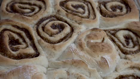 sliding overhead view of freshly baked cinnamon rolls hot from the oven