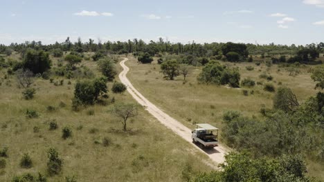 Statische-Luftaufnahme-Eines-Safari-Autos,-Das-Tagsüber-In-Imire-Simbabwe-Eine-Straße-Entlang-Fährt