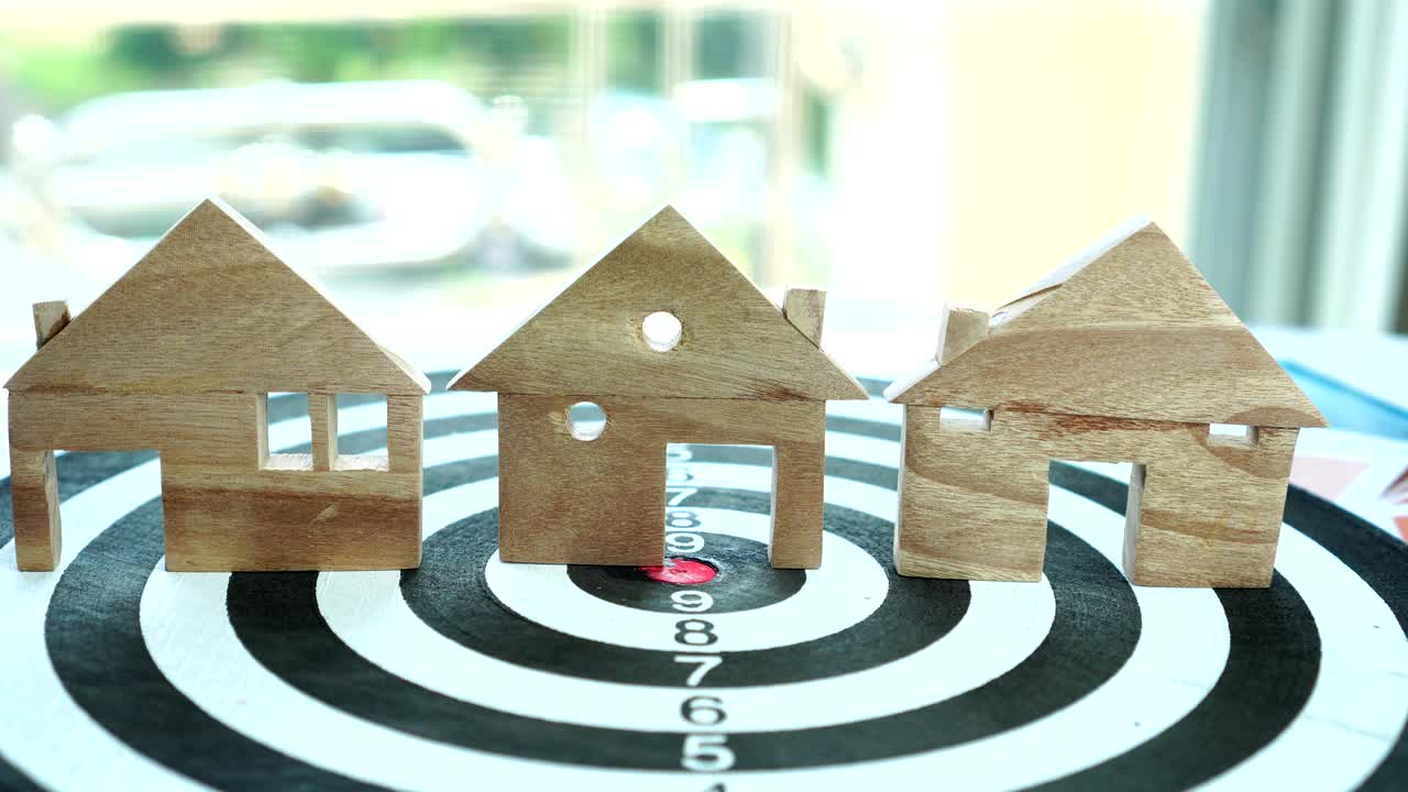 다트보드에서 집 모델을 손으로 선택하십시오. 집을 구입하기 위해 모기지 투자 자산 사업을 선택하고 돈을 절약하는 개념.