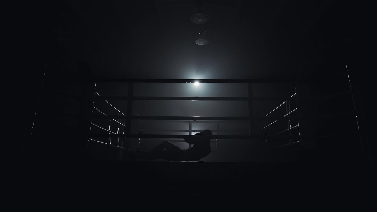 Karanlık boks ringinde mekik çeken atletin silüeti