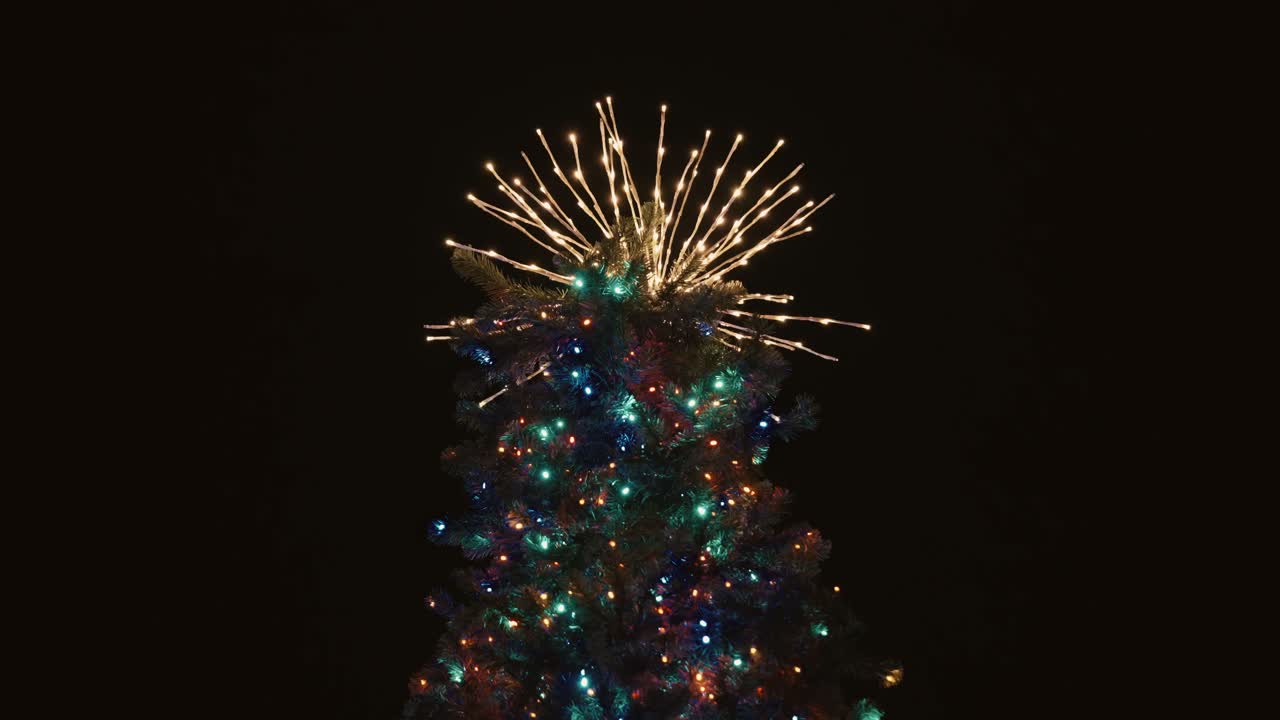 luces estelares abstractas en la parte superior del árbol de navidad contra un fondo negro
