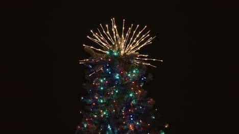 abstract stary lights atop christmas tree against black background