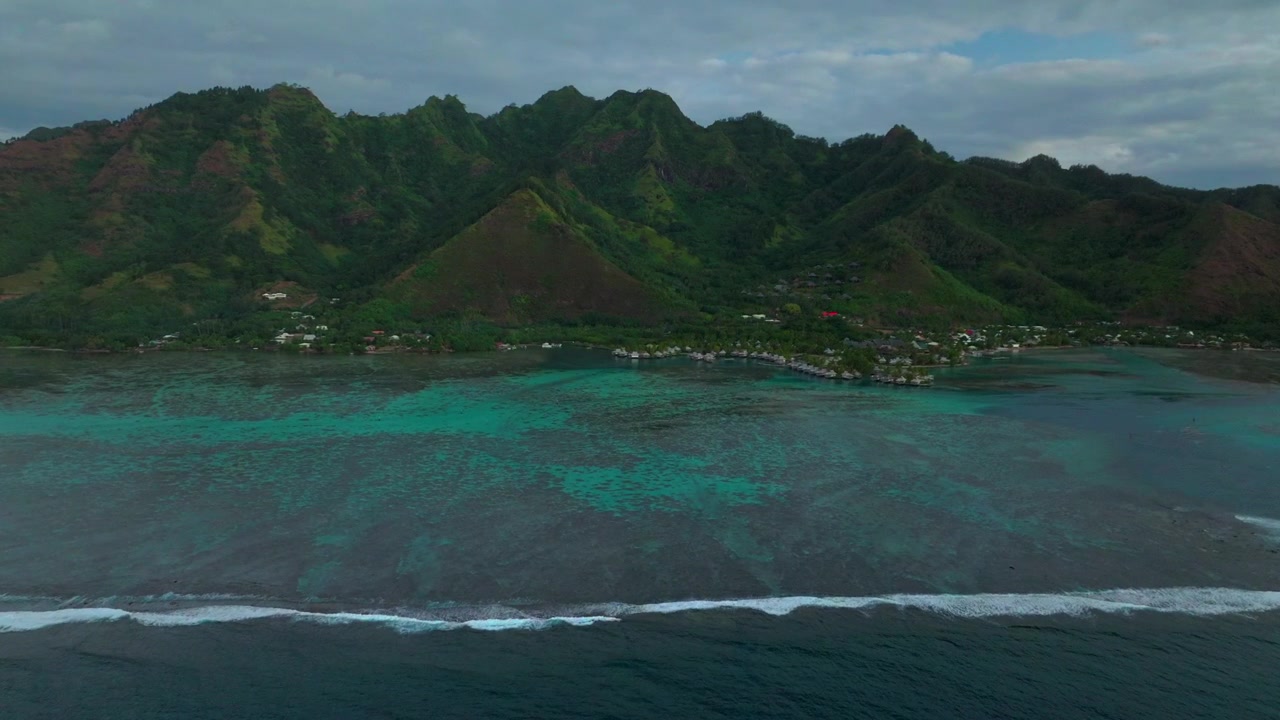 Bungalows Cooks Opunohu Bay Moorea island French Polynesia aerial drone morning clouds boats Passe lagoon coral reef waves Mount Mauaroa Tohivea Rotui Haapiti Pacific Ocean forward pan up motion