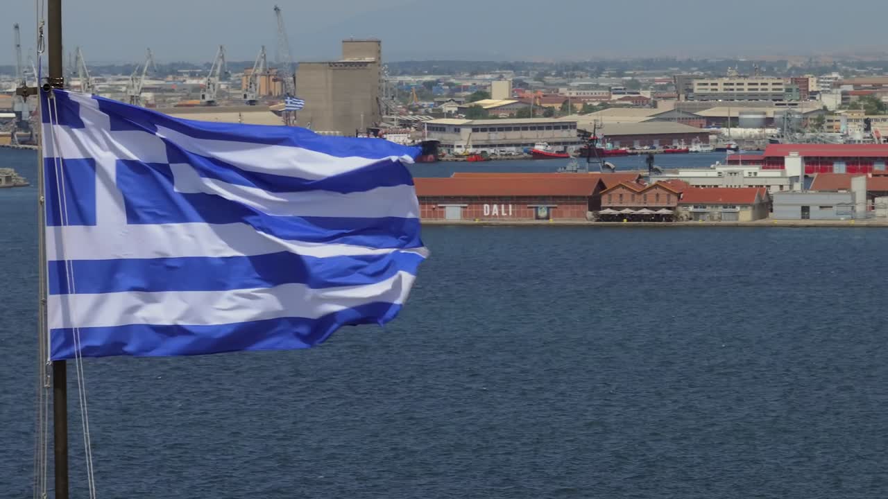 Greek Flag Waving Over City Harbor