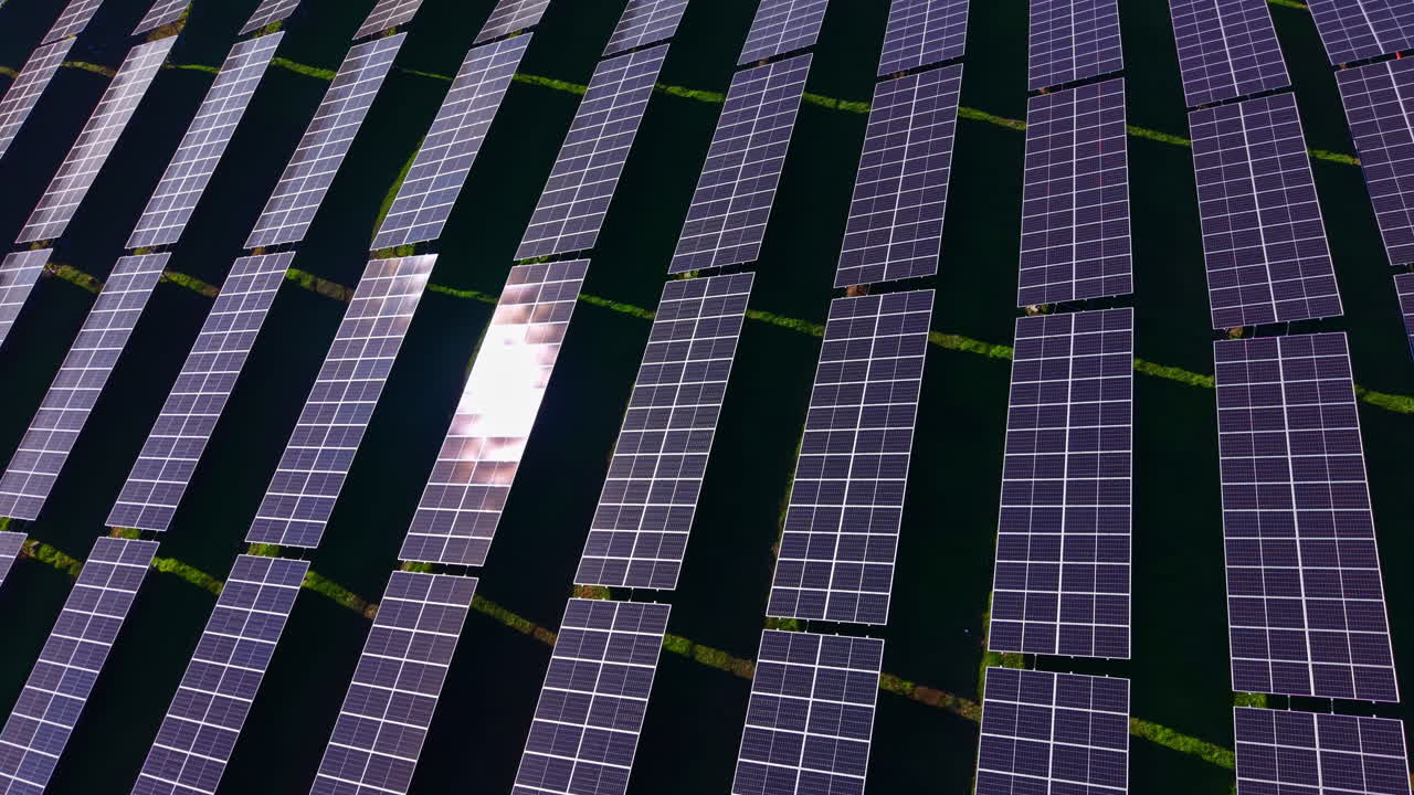 Vasti pannelli solari si estendono su un campo soleggiato sotto un cielo azzurro brillante, catturando energia rinnovabile in un paesaggio sostenibile con file e file di moduli scintillanti