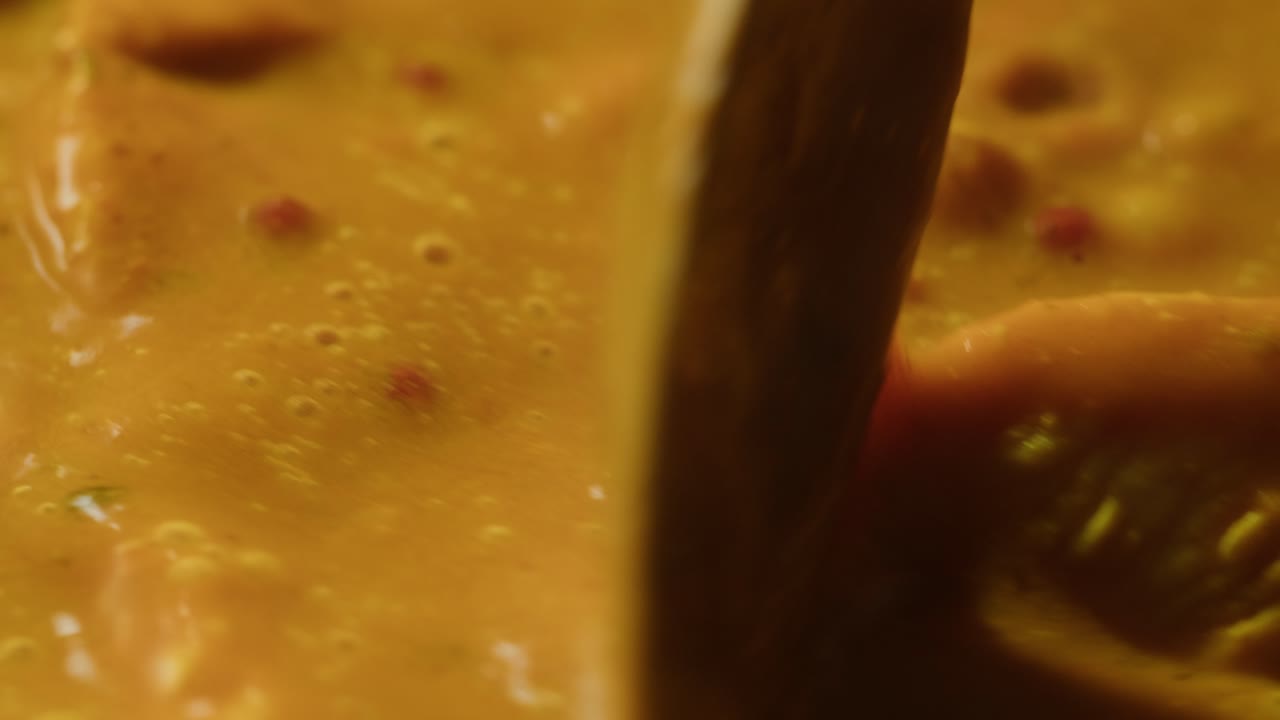 Yellow boiling sauce on pan close-up. Asian cuisine concept. Curry is a dish with a sauce seasoned with spices. Curries may contain fish, meat, poultry, or shellfish, either alone or in combination with vegetables. Others are vegetarian.