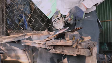 worker sharpening a broad blade with a grinding wheel