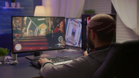 Back-view-of-pro-man-gamer-sitting-on-gaming-chair-at-desk