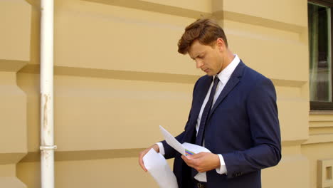 hombre de negocios serio leyendo documentos al aire libre. papeles de aspecto profesional