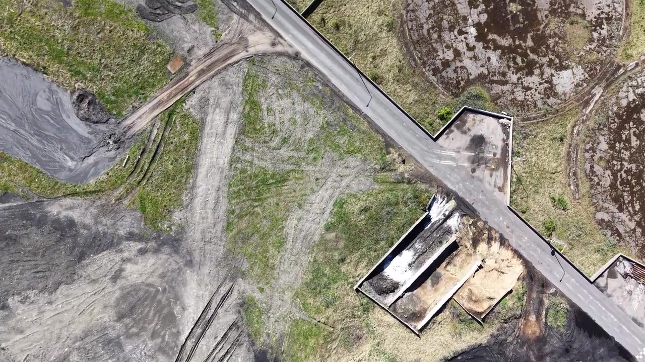 A tracking drone shot providing a top-down view of the coal yard and industrial access roads at the Studstrup Power Station.