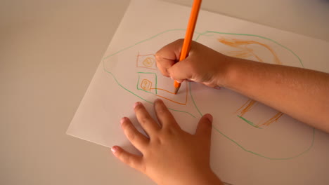 a child drawing on paper with coloured pencils