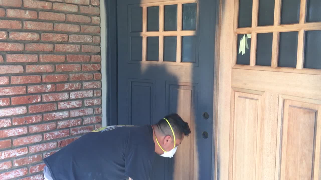 스프레이 건으로 목재 문에 목재 프라이머를 바르는 전문 화가