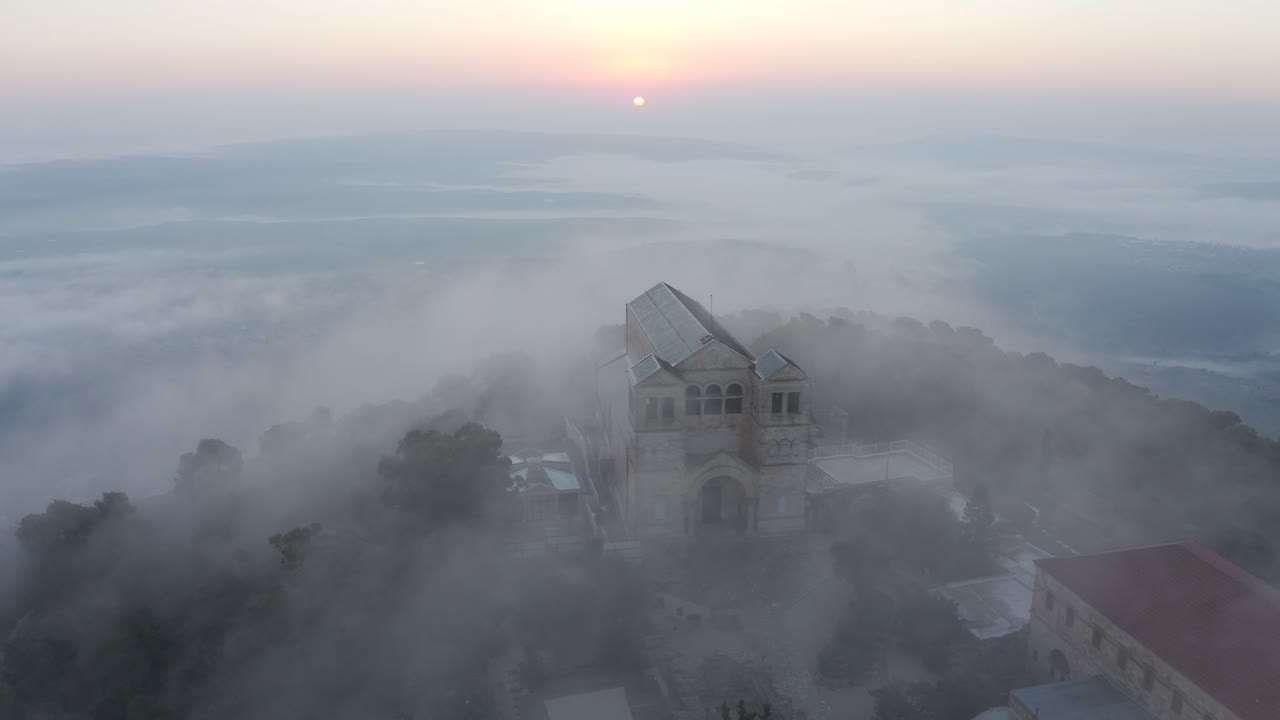 산꼭대기 교회 위의 안개가 가득한 해가 뜨는 것