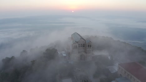 amanecer brumoso sobre la iglesia de la cima de la montaña