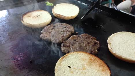 a chef's hands turning grilled corned beef and bread on a grate