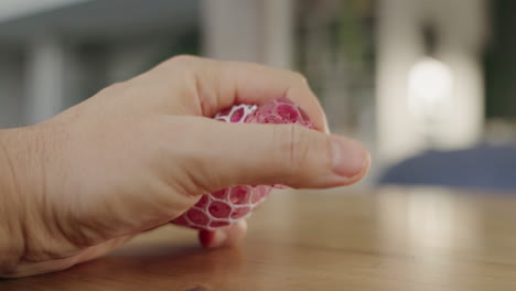 person squeezing a pink glitter stress ball on a table