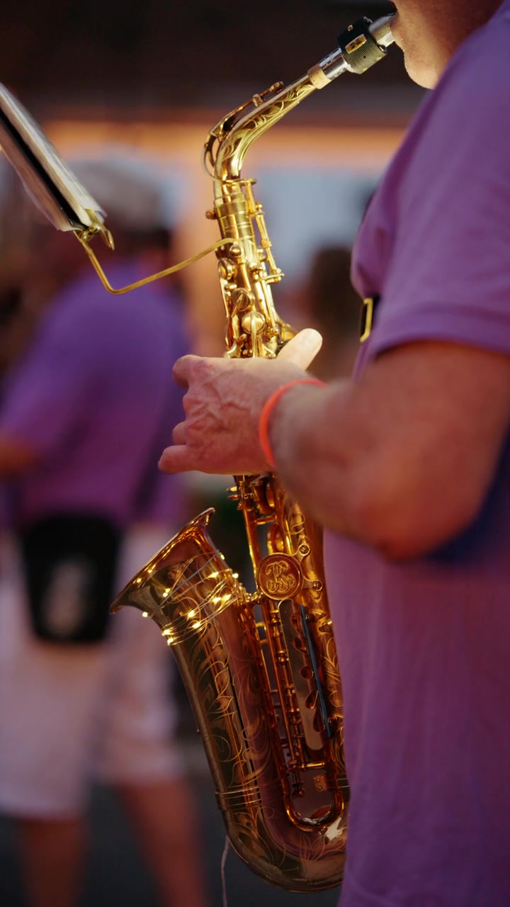 Mani di un musicista che manipolano abilmente i tasti su un sassofono dorato, esibendosi dal vivo in un vivace evento musicale.