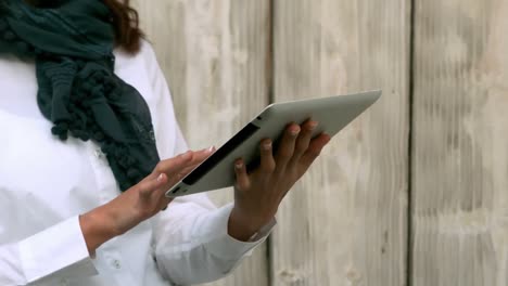 Hipster-using-tablet-against-wooden-fence