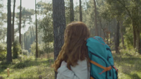 side view of a red haired woman backpacker hiking in the forest on a sunny day