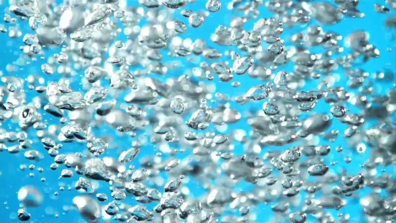 Bolle d'aria scintillanti che salgono in acqua blu al rallentatore