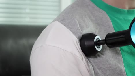 vista aislada de un hombre que usa una pistola de masaje eléctrica en los músculos de su hombro