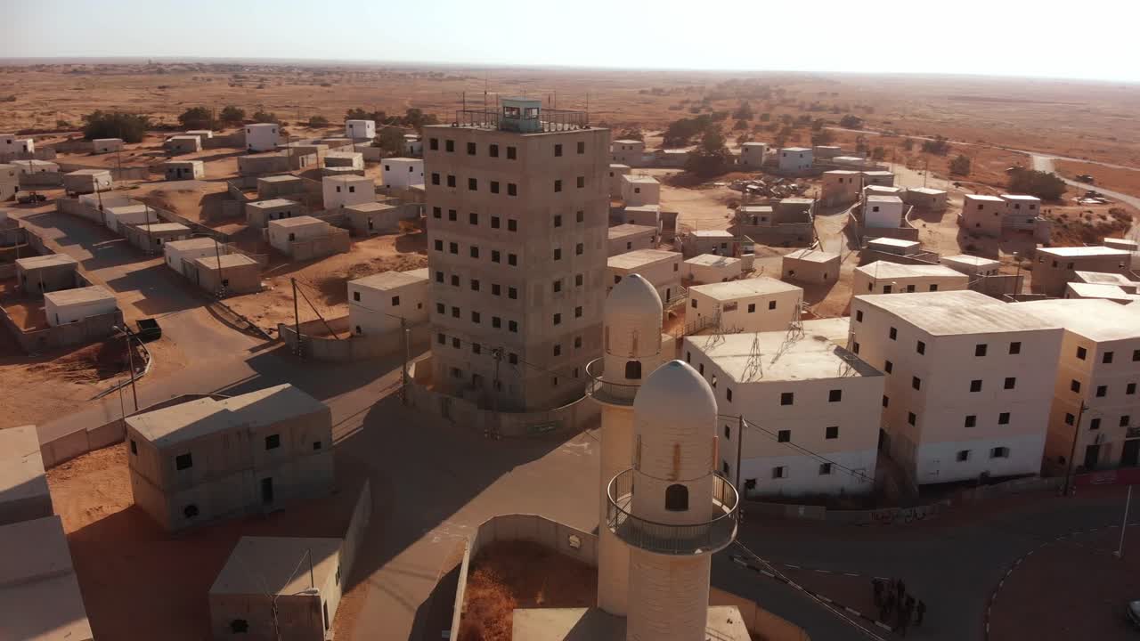 aerial shot of two mosques and big building in an old empty city in the desert in palestine near Gaza while camera orbit around them at sunset.