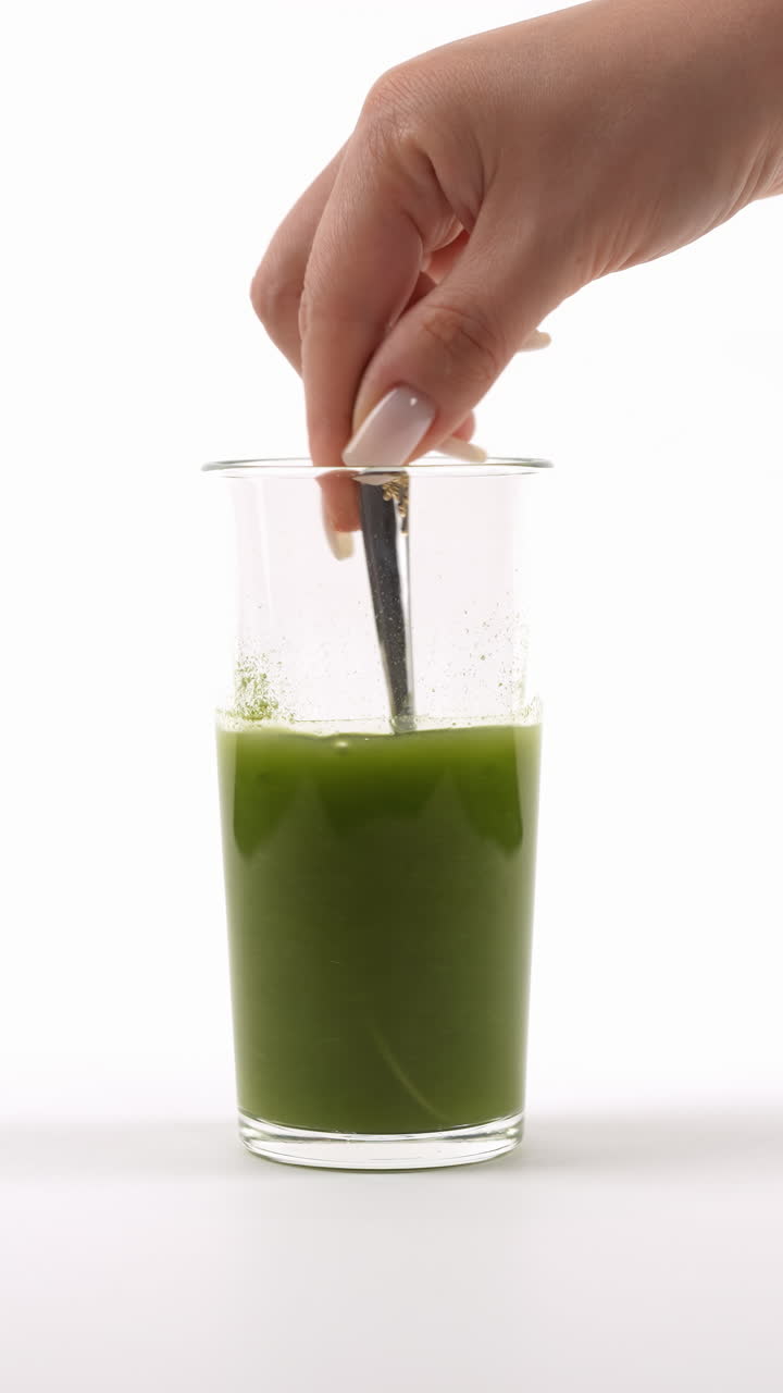 vidrio transparente con polvo verde que se mezcla con un tenedor, creando burbujas en un entorno blanco