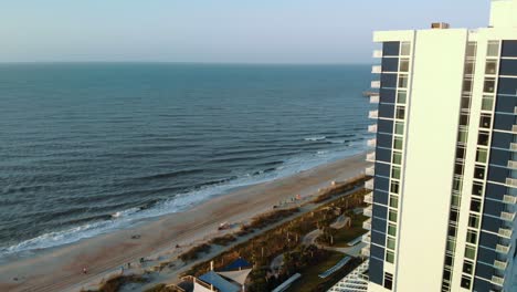 Aerial-push-in-shot-toward-beach-past-hotel-during-golden-hour