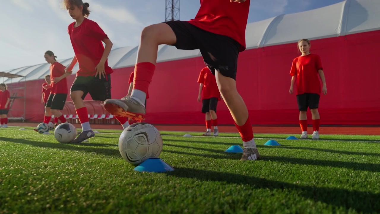 Giovani calciatrici che si allenano nel dribbling sul campo