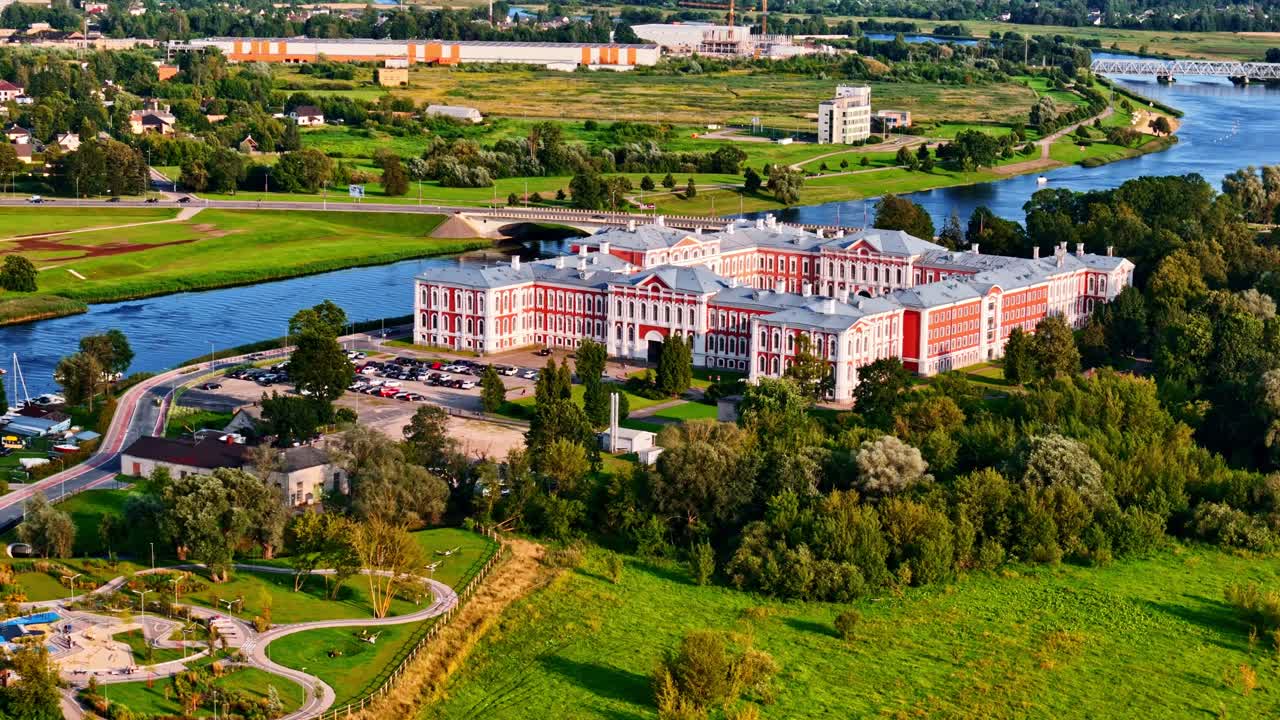 Jelgava Palace in Latvia captured from air, surrounded by Lielupe river with golden hour sunlight