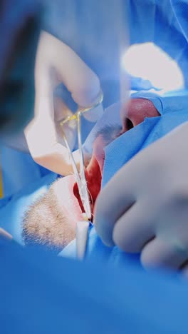 hands in gloves sew soft gum tissue after tooth implant during oral surgery