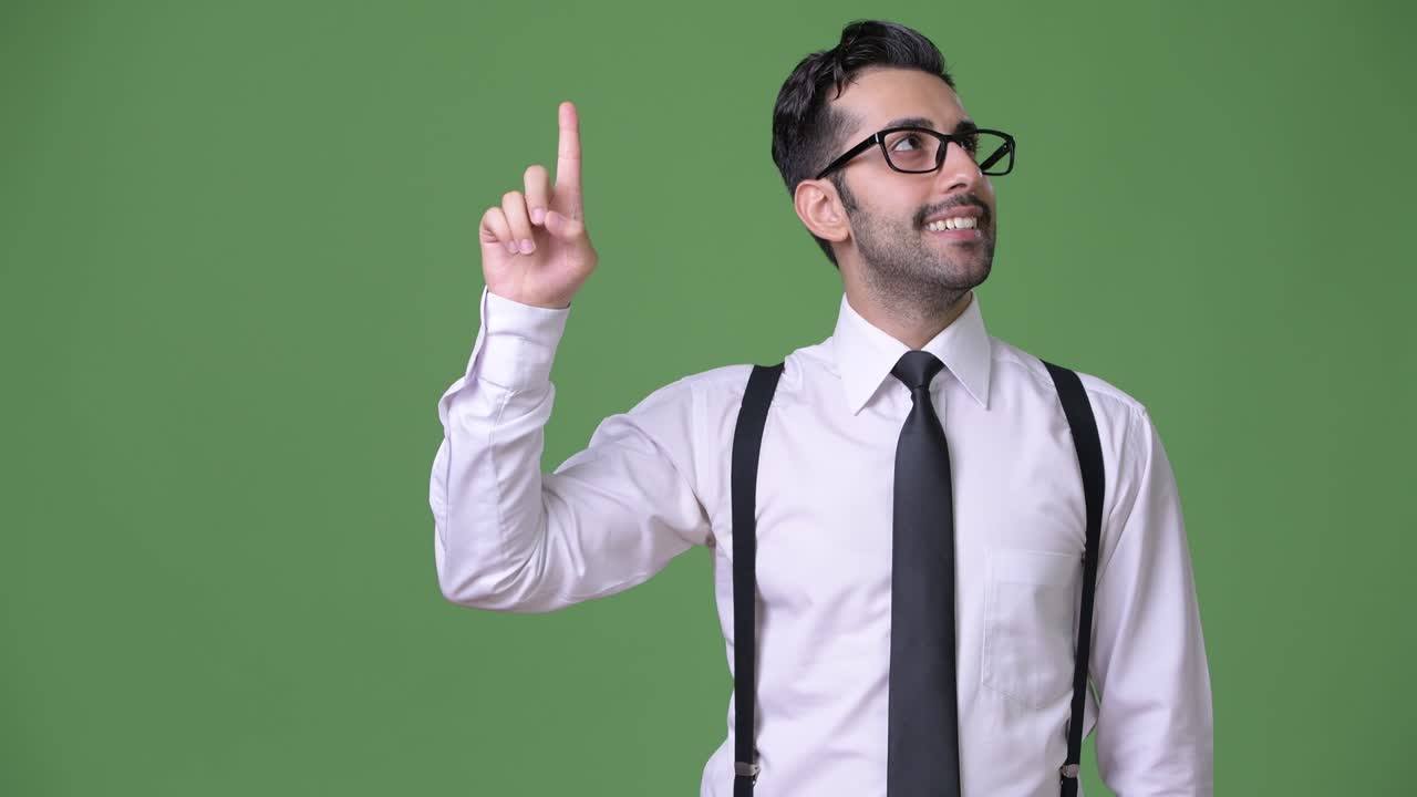 joven empresario persa barbudo y guapo contra un fondo verde