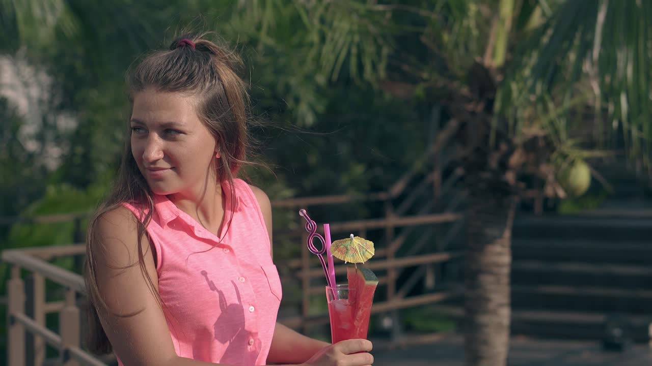 mujer delgada sostiene cóctel y largas olas de cabello marrón lentamente