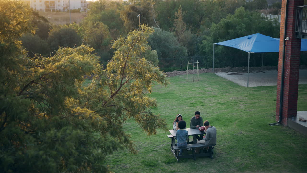 People sitting at a picnic table on the lawn
